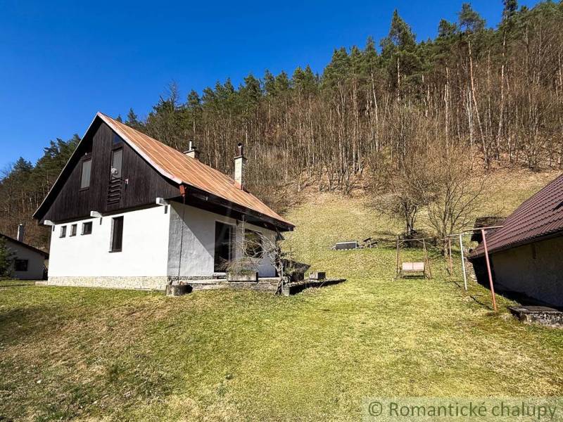 A cottage in Moštenica surrounded by a grassy plot and forest in the background.