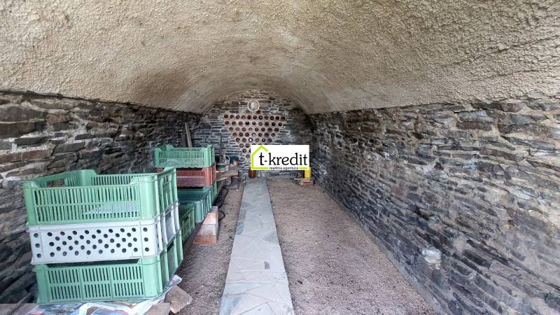 Stone cellar with shelves and plastic crates in Vinice.
