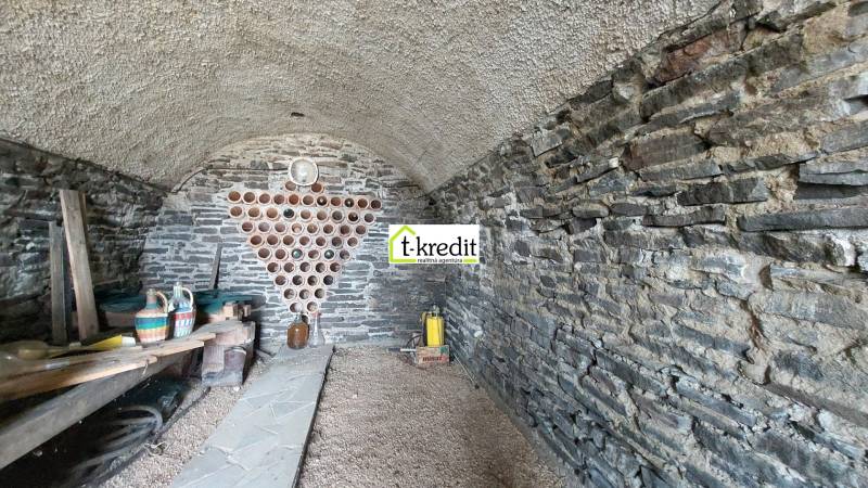 Stone cellar in the vineyard with storage space for wine and a shelf for containers.