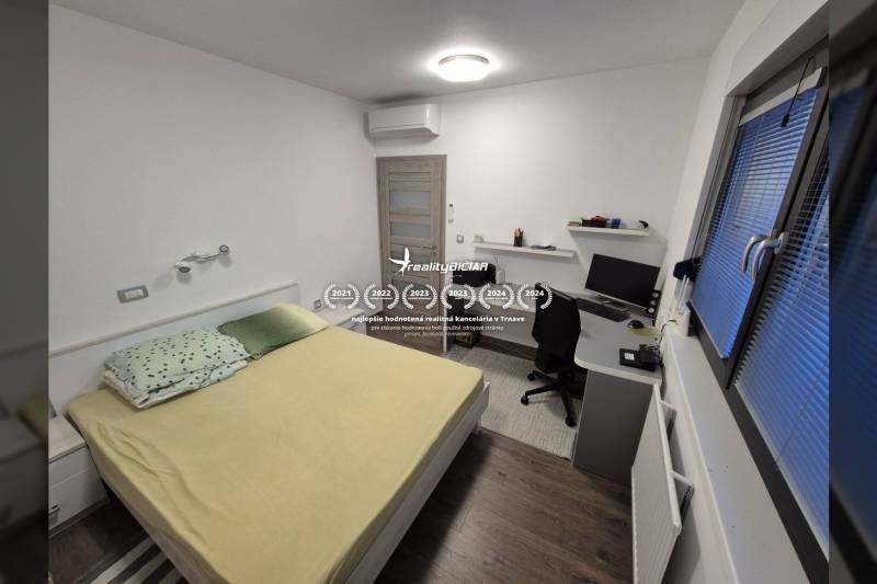 A bedroom in a family house with a desk and a wooden decor floor.