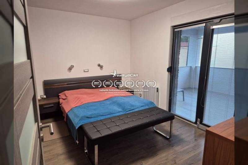 Bedroom in a family house with a wooden decor floor and access to a balcony.