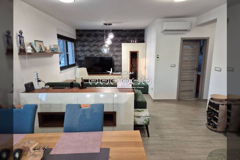 Living room with a television, wooden decor flooring, sofa, and decorative wall.