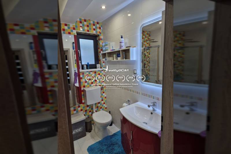A bathroom in a family house with colorful tiles and light walls.
