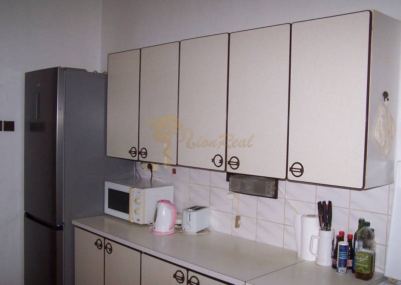 A kitchen unit in a 2-room apartment with a refrigerator, microwave, and kitchen accessories.