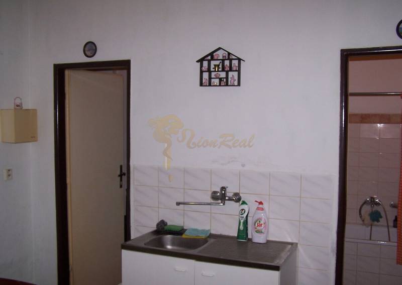 A kitchenette with a hanging dish rack by the sink in a 2-room apartment.