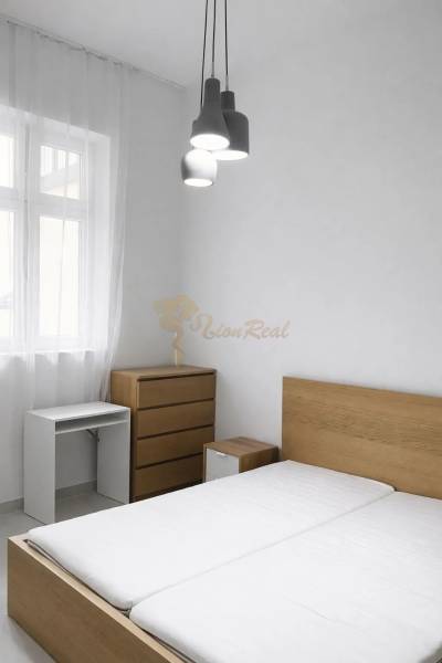 A bedroom with wooden furniture and pendant lighting in a two-room apartment.