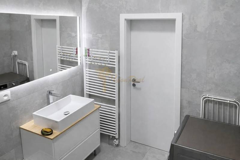 Bathroom in a 2-room apartment with a sink, mirror, and towel rack.