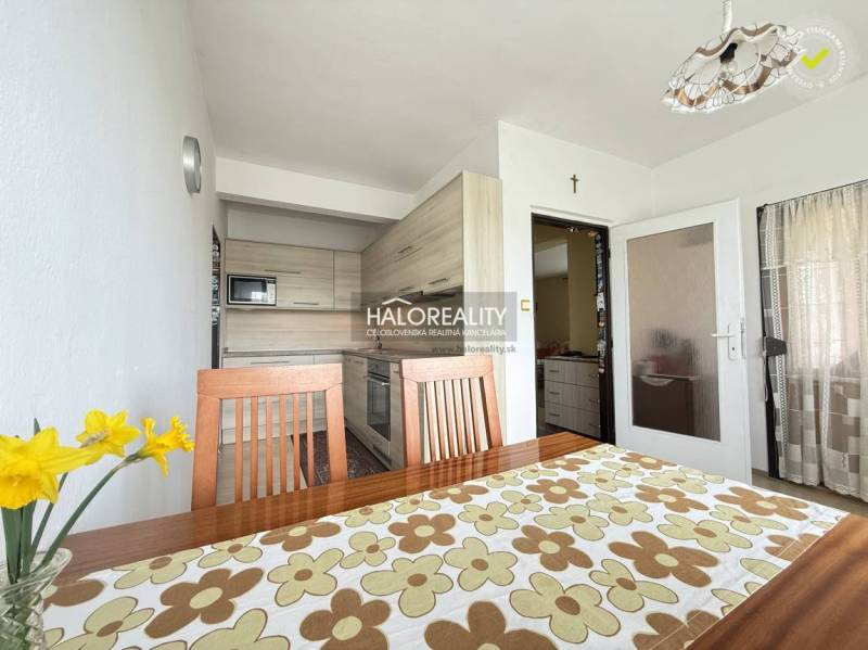A bright kitchen in a family house with wooden furniture and a decorative tablecloth.