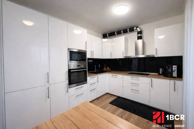 A kitchen in a 3-room apartment with white cabinets and a wood-patterned floor.