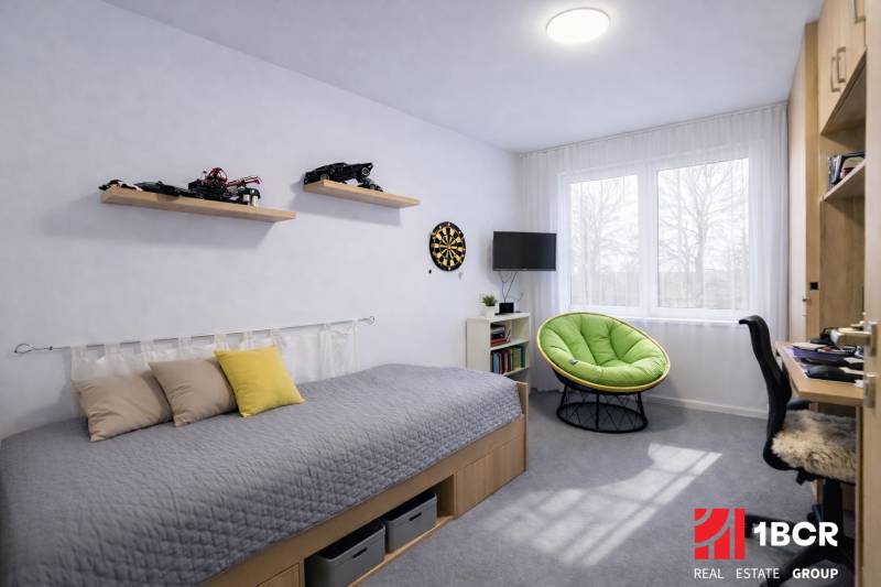 Children's room in a 3-room apartment with a bed, toys, and a green armchair.