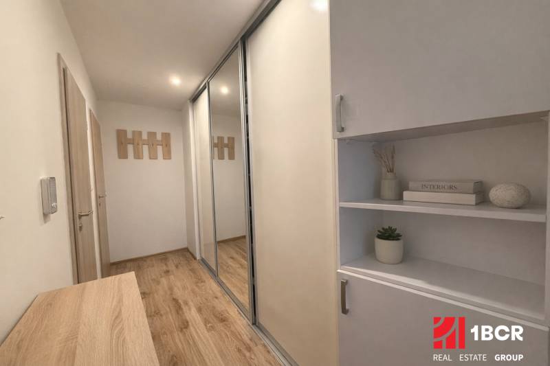 A hallway in a 3-room apartment with a wooden-patterned floor and built-in wardrobes.