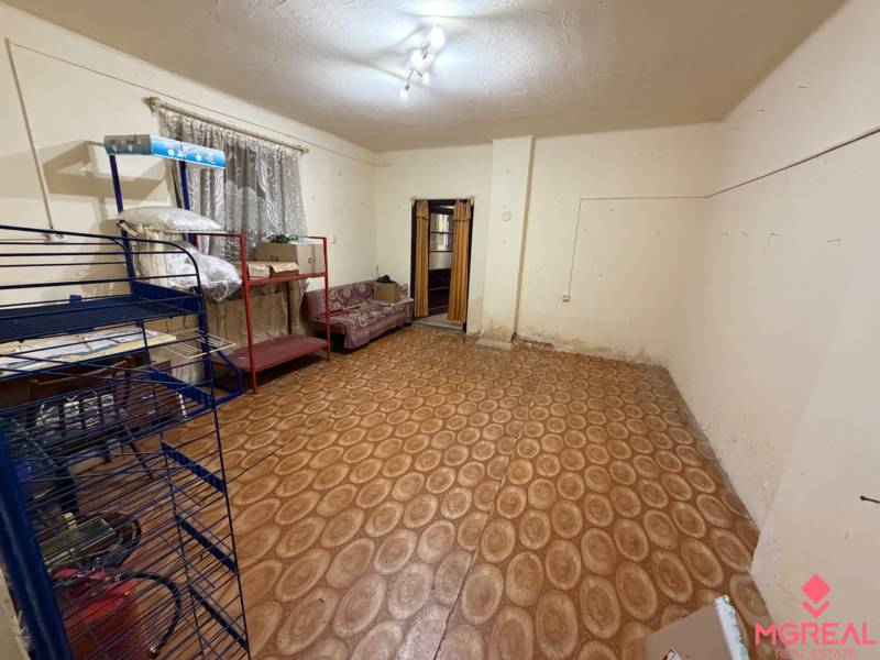 A room in a family house with a floor featuring a wooden decor and simple furniture.
