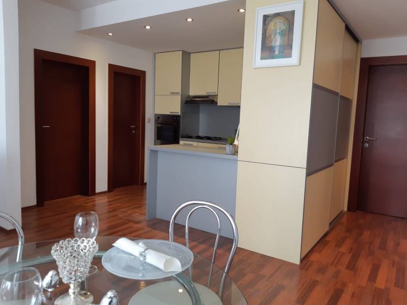 Dining area and kitchen in a 3-room apartment with a wooden decor floor.