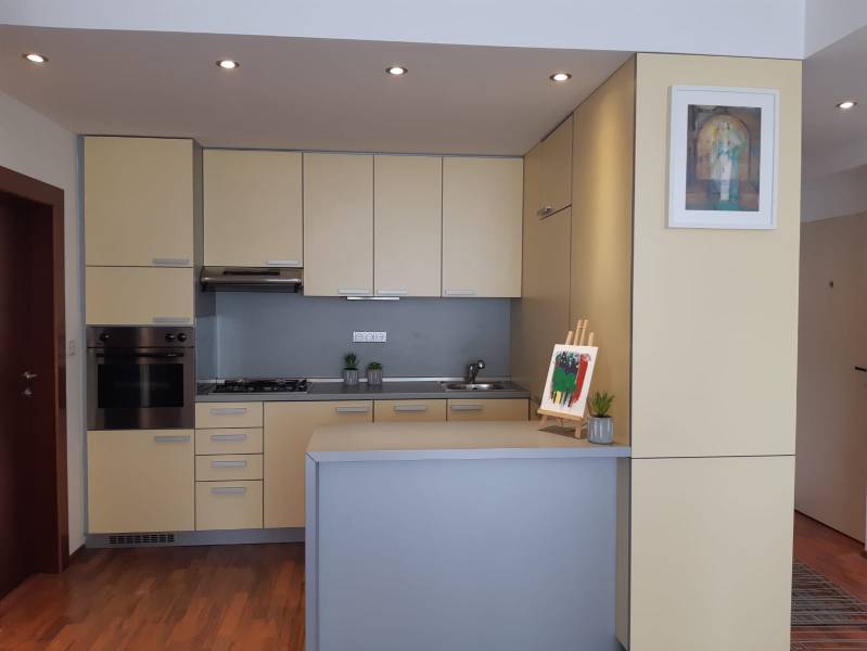 A kitchen in a 3-room apartment with light cabinets and a floor with a wood design.