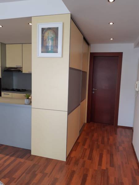 Interior of a 3-room apartment with wood-patterned flooring, a kitchen, and a built-in wardrobe.