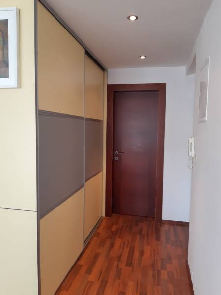 A hallway in a 3-room apartment with a wooden decor floor and a built-in wardrobe.