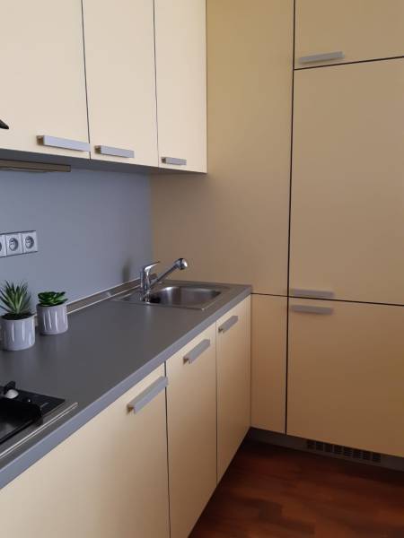 A kitchen in a 3-room apartment with cream cabinets and a wooden decor floor.