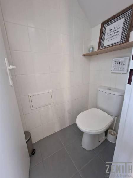 A restroom with white tiles and a decorative shelf in commercial premises.