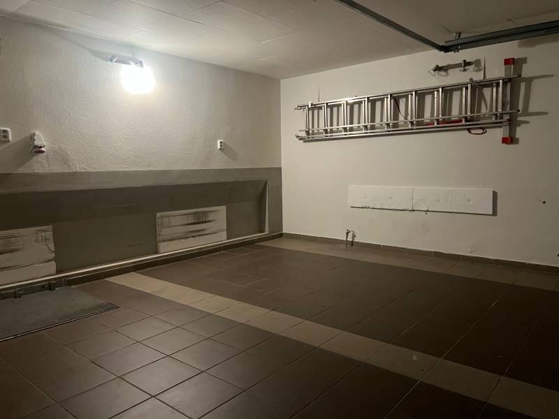 A garage in a family house with ceramic tiles and a ladder on the wall.