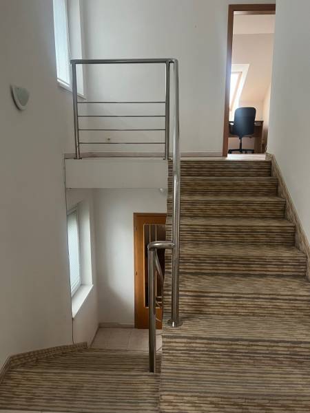 A staircase with a railing leads to a room in a family house, white walls.