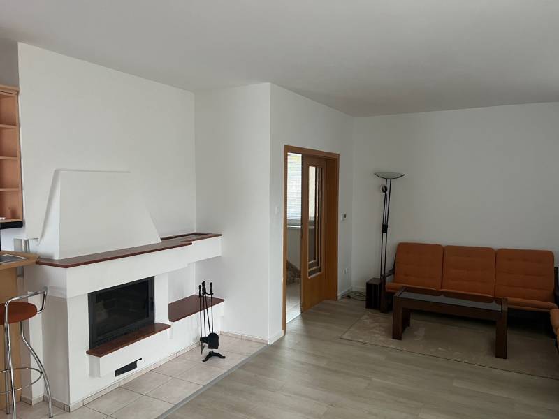 Living room with a fireplace, orange sofa, wood-patterned floor, and glass table.