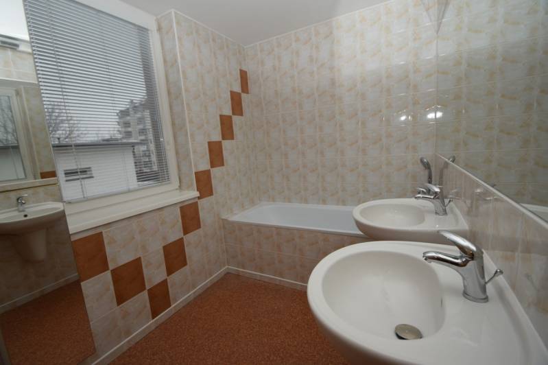 A bathroom with a bathtub, two sinks, a window, and decorative tiles in a family house.