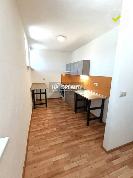 A kitchen in a 2-room apartment with a wooden decor floor and white walls.