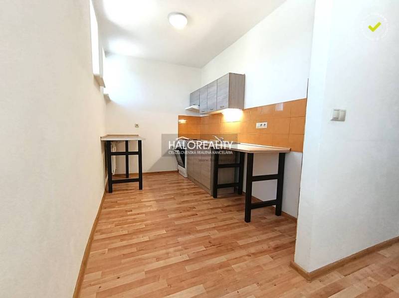 A kitchen in a 2-room apartment with a wooden decor floor and orange tiles.
