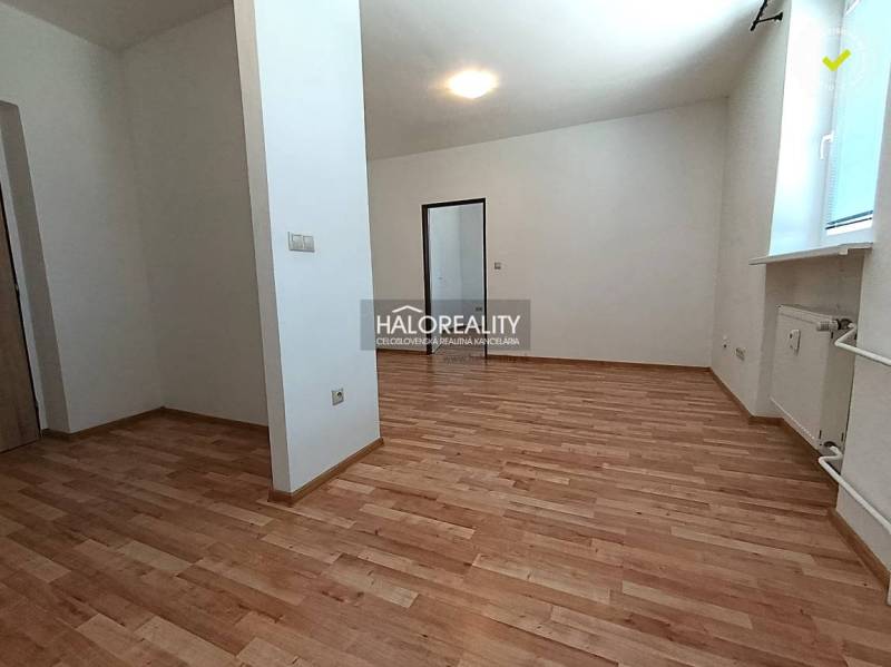 A spacious room in a 2-room apartment with a wooden decor floor and white walls.