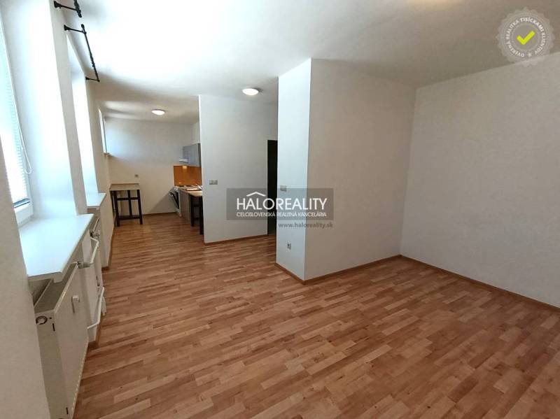 Spacious interior of a 2-room apartment with a wooden decor floor and a kitchen.