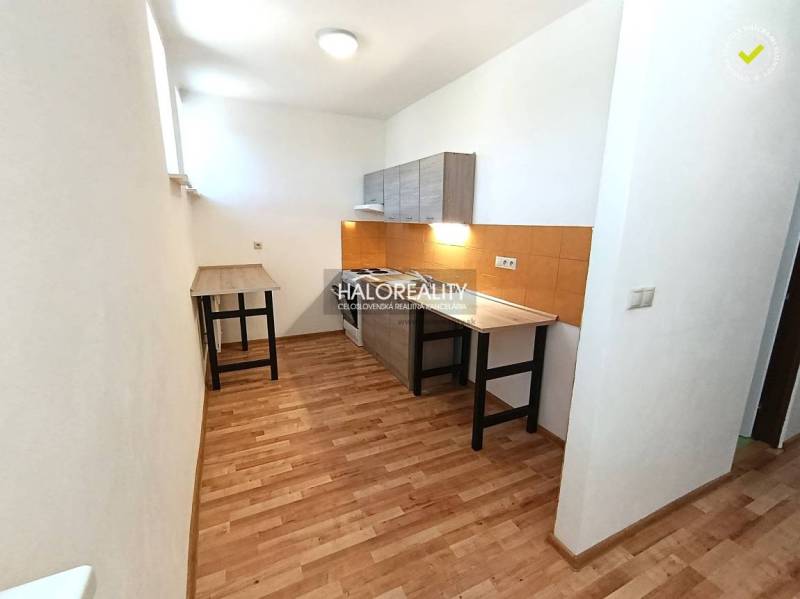 A kitchen in a 2-room apartment with a wooden decor floor and orange tiles.