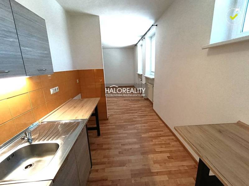 A kitchen in a 2-room apartment with a wooden decor floor and orange tiles.