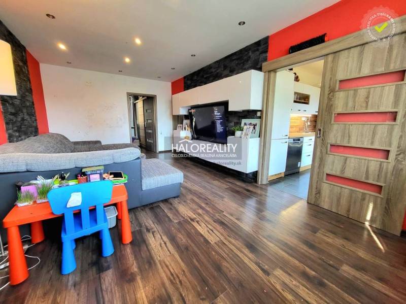 Living room in a three-room apartment with a wooden-patterned floor and colorful children's furniture.