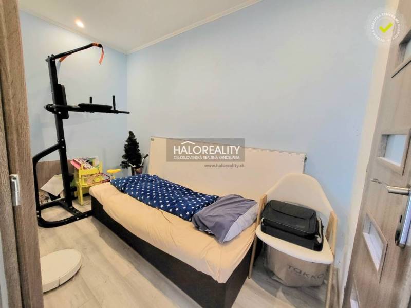 A room in a 3-room apartment with a bed and exercise equipment, wooden decor flooring.