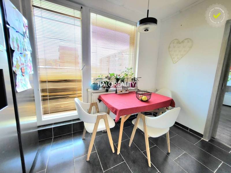 Dining area in a 3-room apartment with a tiled floor and large windows.