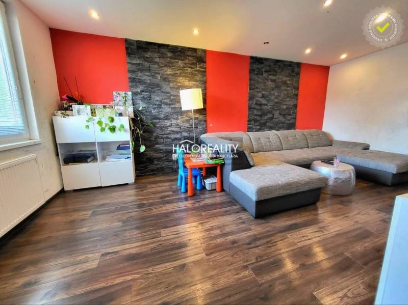 Living room in a 3-room apartment with a comfortable sofa and a wooden-patterned floor.