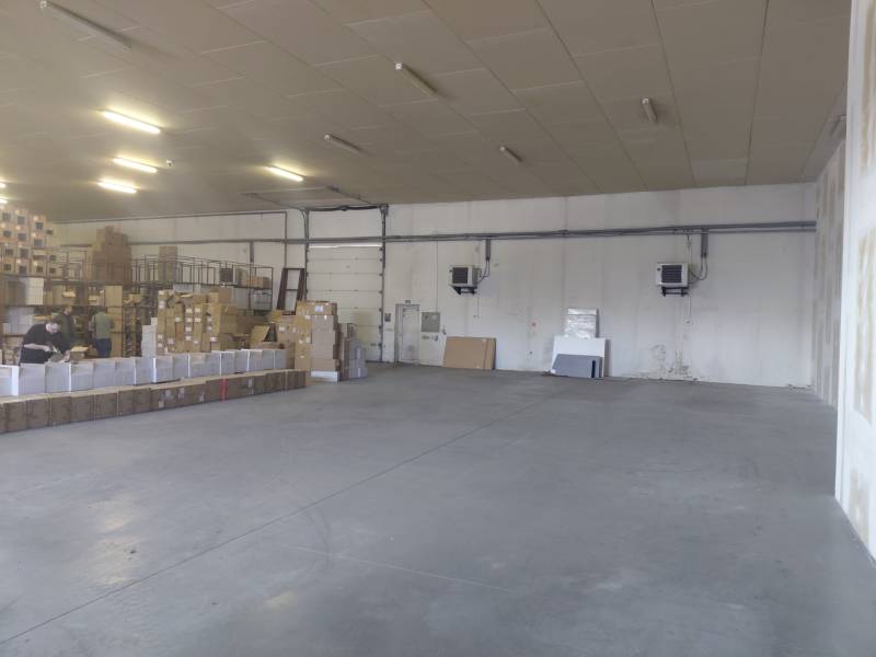 Spacious interior of warehouses and halls with cardboard boxes and workers.