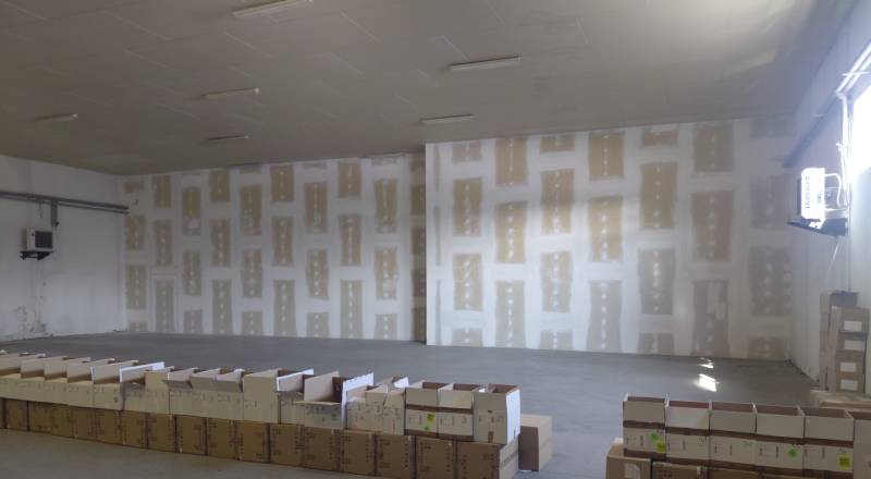 Empty warehouse with concrete floor and scattered cardboard boxes.