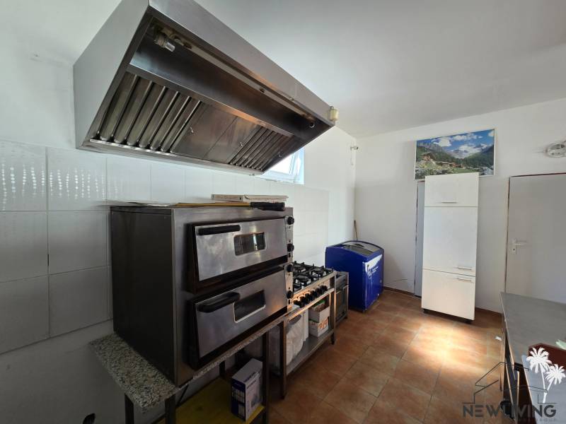 Gastro premises with an oven, extractor hood, and refrigerator, floor with wooden decor.