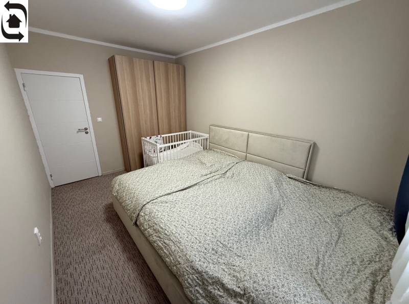 A bedroom with a gray bed, a baby crib, and a wardrobe in a 4-room apartment.
