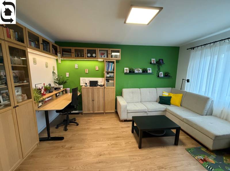 Living room with a sofa, a desk, and a wooden decor floor in a 4-room apartment.