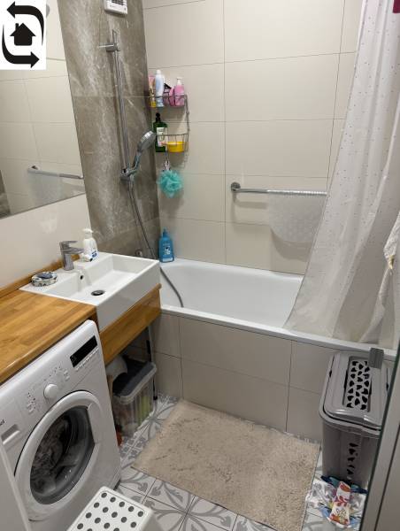 Bathroom with a shower bath and washing machine in a 4-room apartment with elegant tiles.