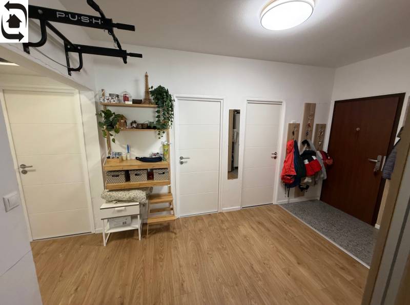 A hallway with four doors, a wooden decor floor, and coat hooks in a 4-room apartment.