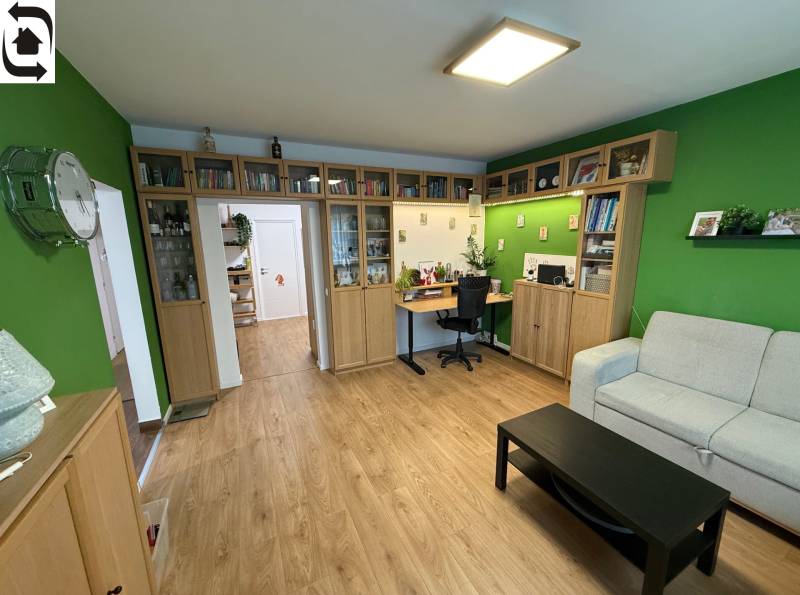 Living room in a 4-room apartment, with a wooden decor floor and a bookshelf.