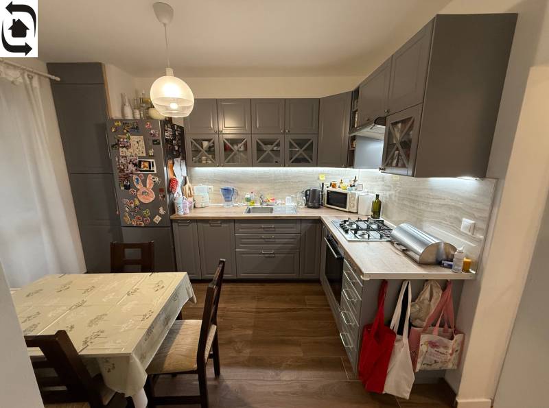 A kitchen in a 4-room apartment with a wooden decor floor and a corner kitchen unit.