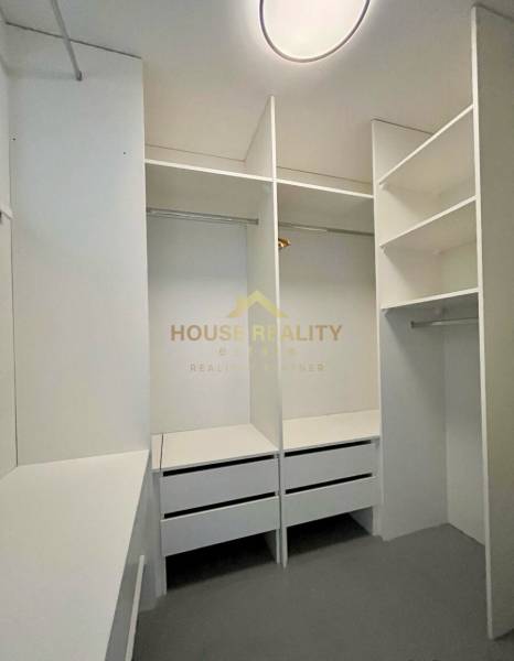 A wardrobe with white built-in shelves and drawers in a 3-room apartment.