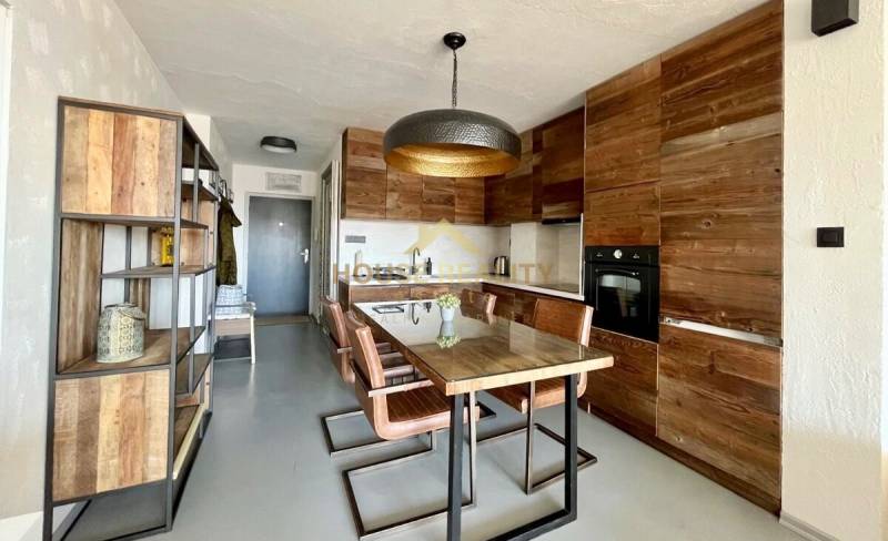 A kitchen of a 3-room apartment with a wooden decor and a dining table.