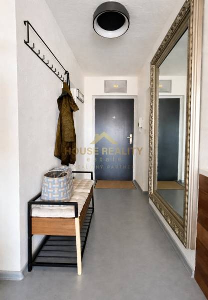 The hallway of a 3-room apartment with a bench, a coat rack, and a large mirror on the wall.