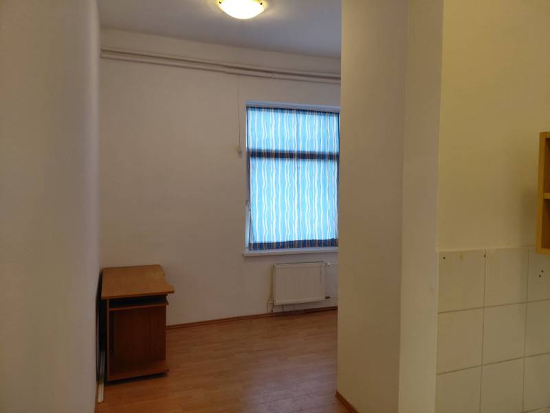 Room with a window, wooden decor flooring, and a table in commercial premises.