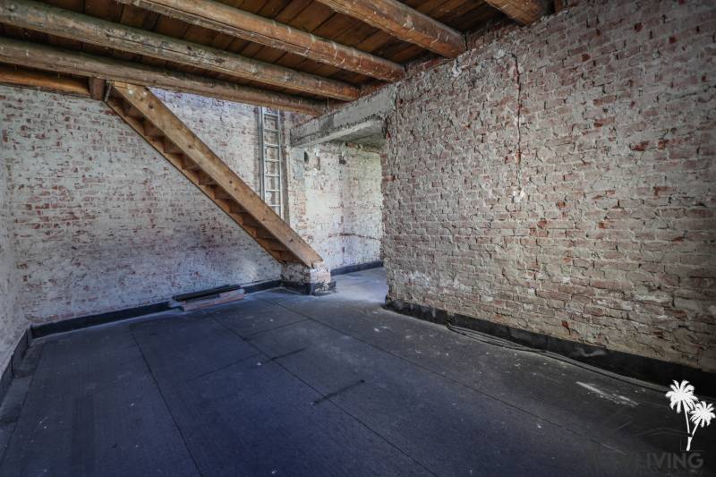 Brick walls and stairs in the attic of a family house with a wooden decor floor.